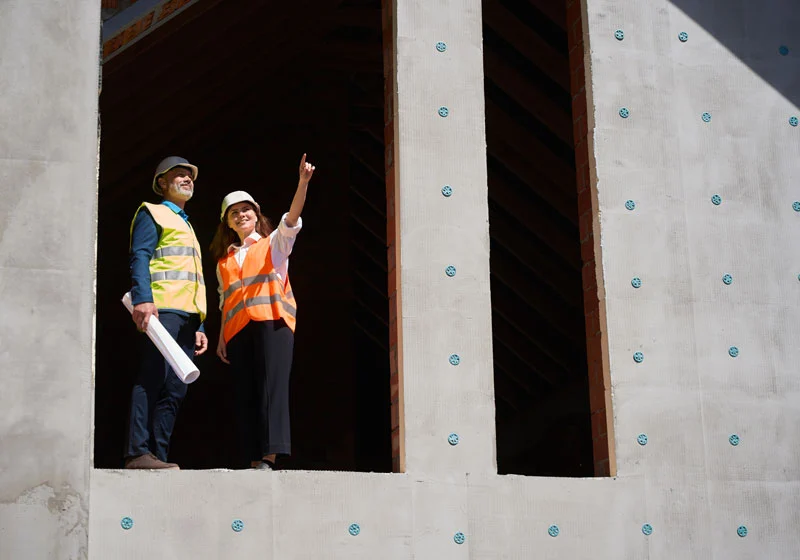 Building engineers standing inside a nearly completed structure, reviewing plans and inspecting the construction progress.