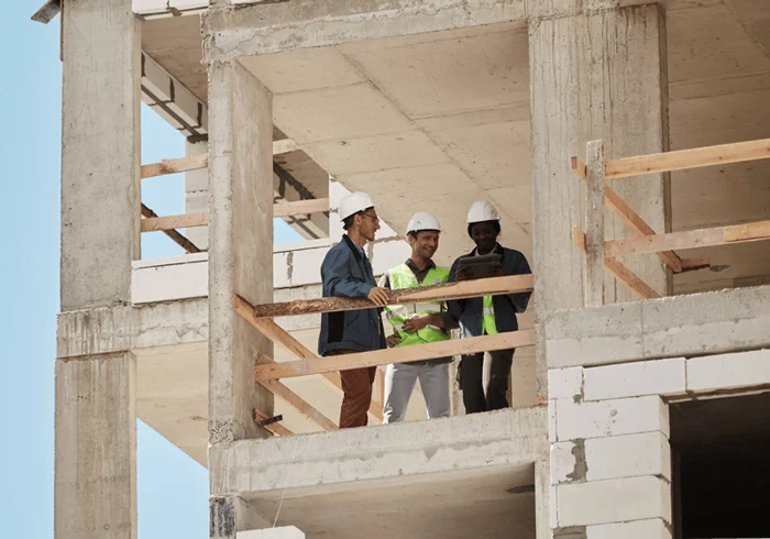 Residential construction site with partially built homes, scaffolding, and workers carrying out building tasks.